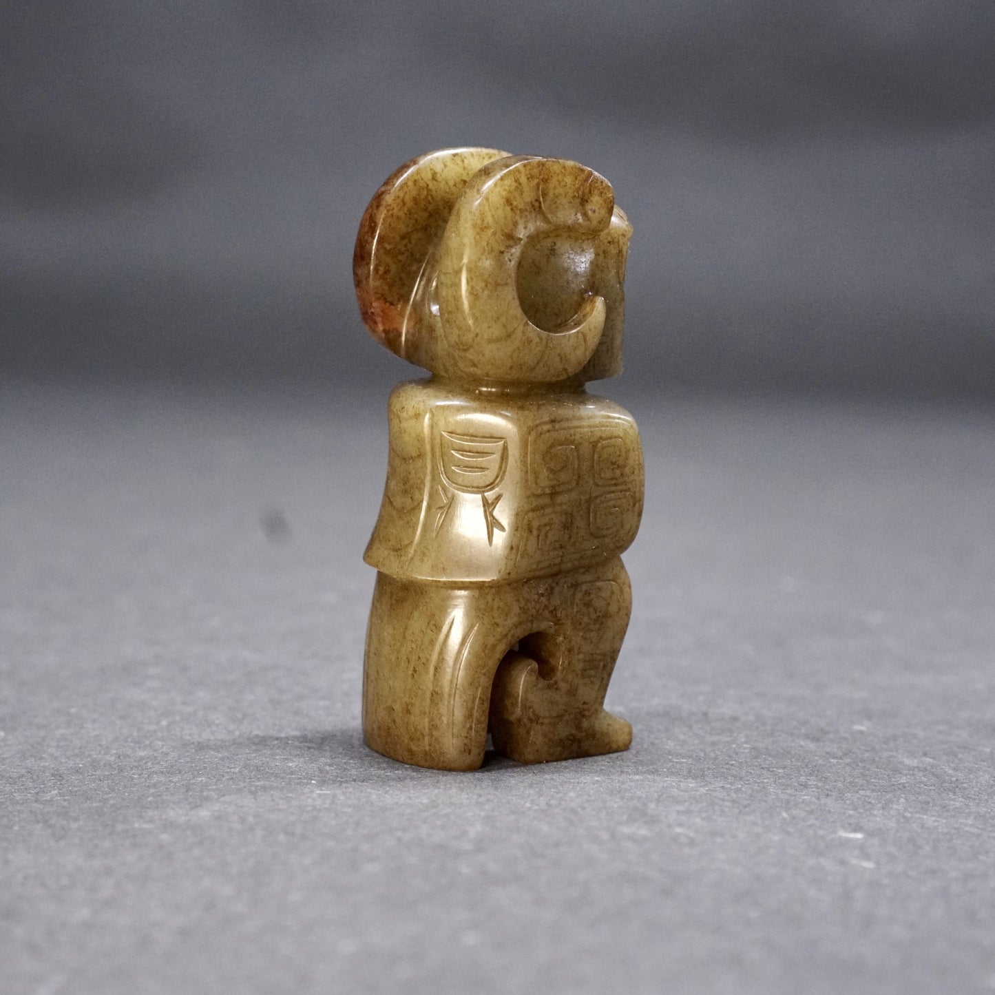 A round jade owl with a human head and ox horns with an inscription on the back