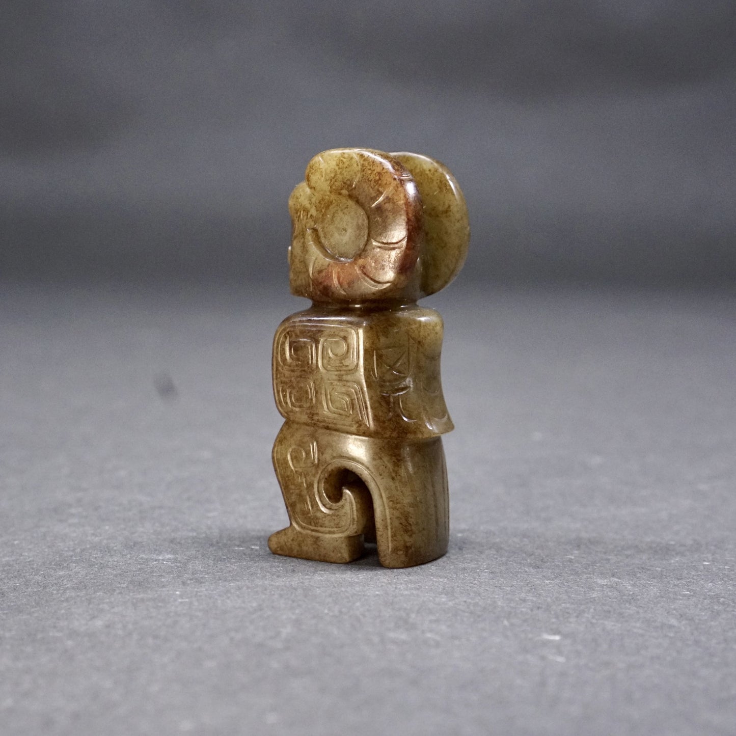 A round jade owl with a human head and ox horns with an inscription on the back