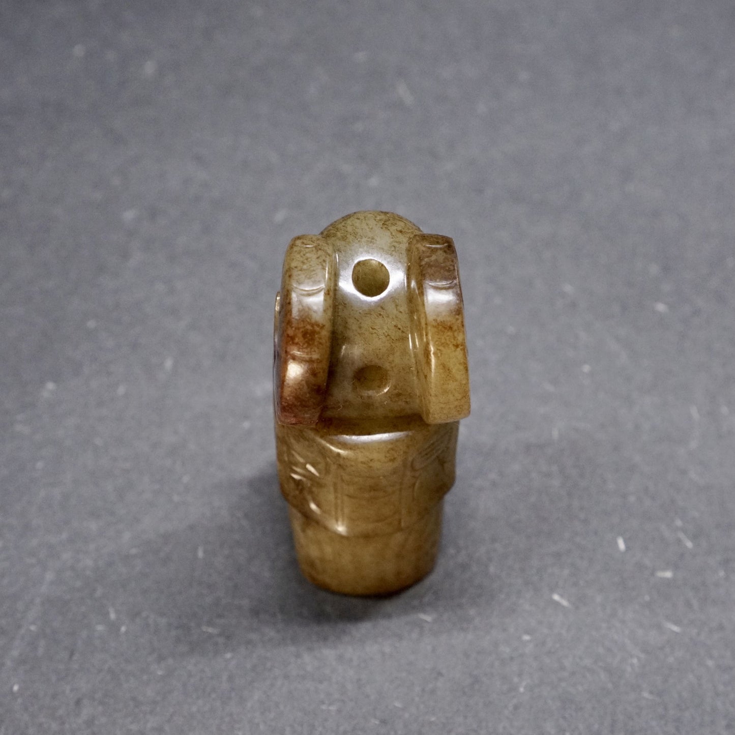 A round jade owl with a human head and ox horns with an inscription on the back