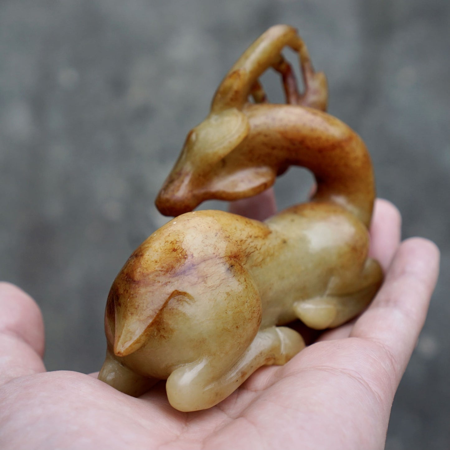 Round-carved sculpture of a lying deer looking back