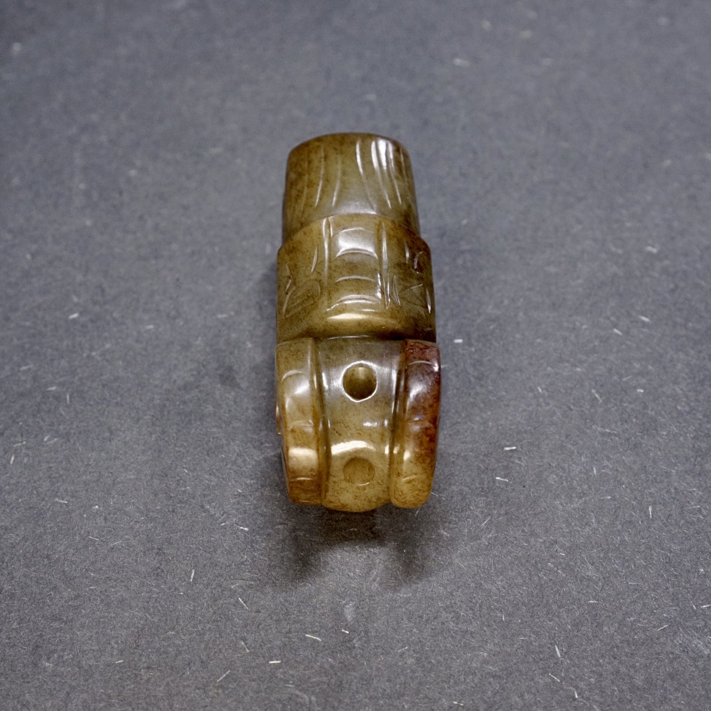 A round jade owl with a human head and ox horns with an inscription on the back